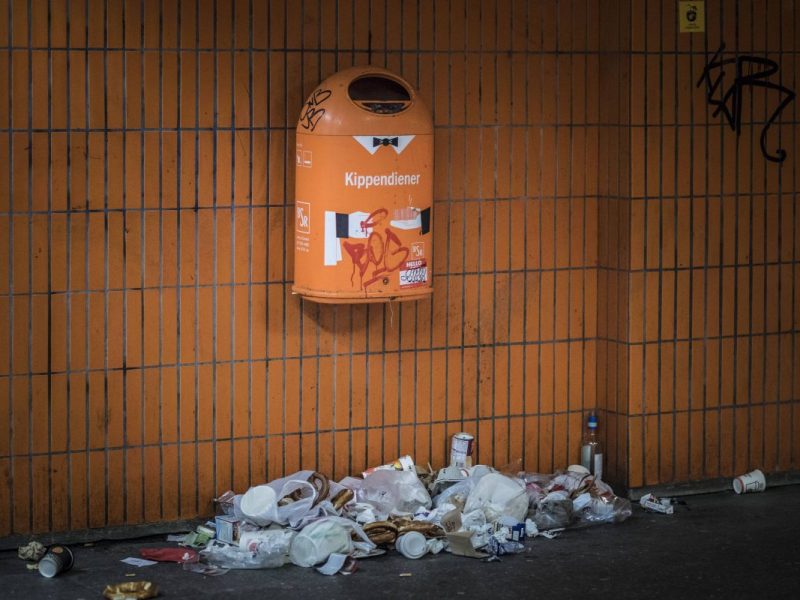 Muell liegt unter einem Muelleimer in Berlin.