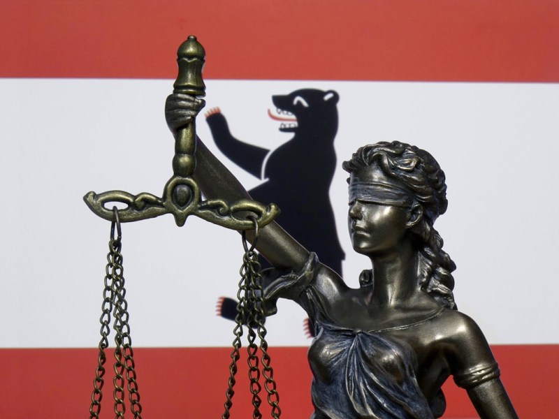 Eine Skulptur der Justitia vor der Berliner Landesfahne.