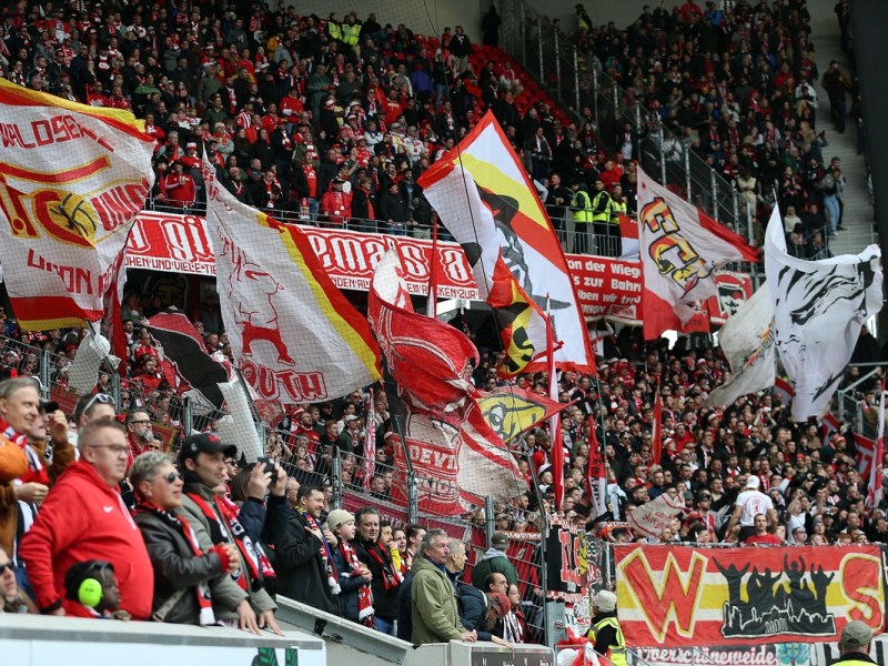 Fans von Union Berlin schwenken im Stadion Fahnen.