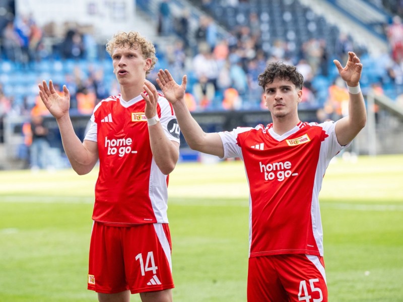 Leopold Querfeld und David Preu von Union Berlin jubeln vor dem Fanblock.
