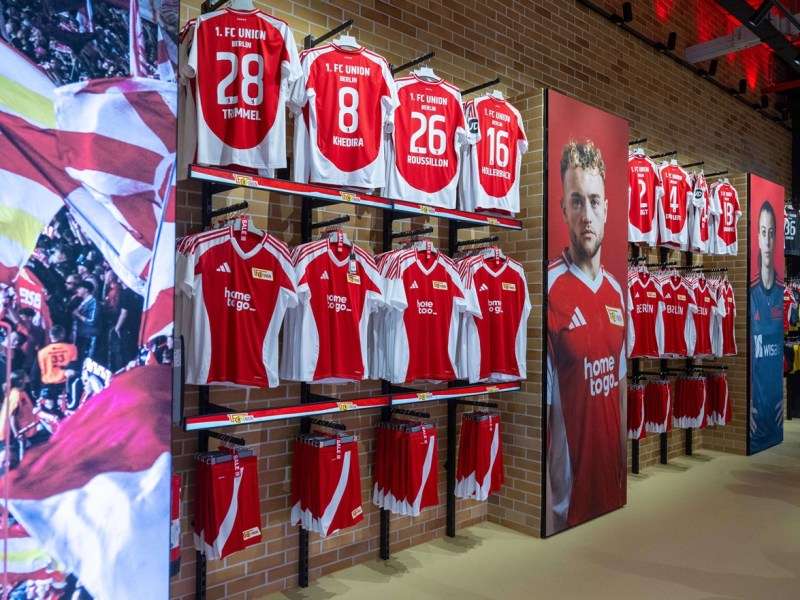 Trikots von Union Berlin hängen in einem Fanshop.
