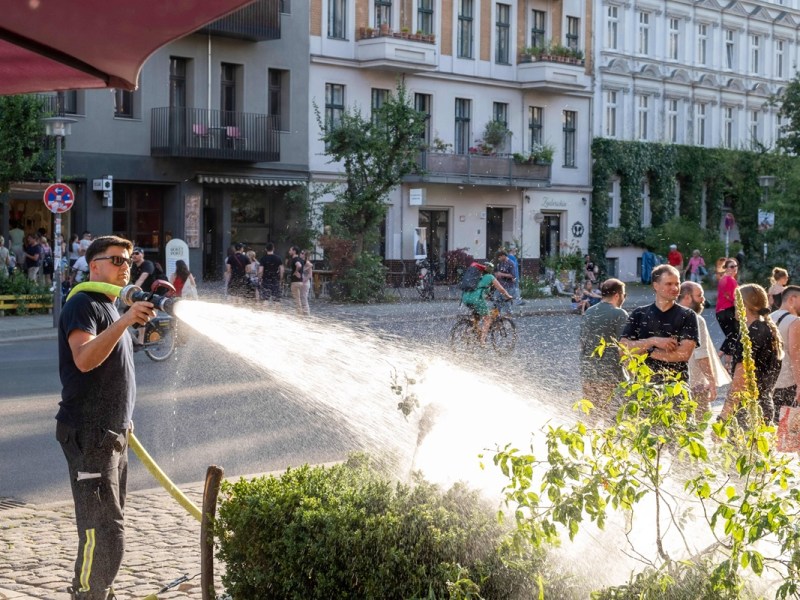 Ein Feuerwehrmann gießt Pflanzen. Das Wetter in Berlin und Brandenburg wird heiß.